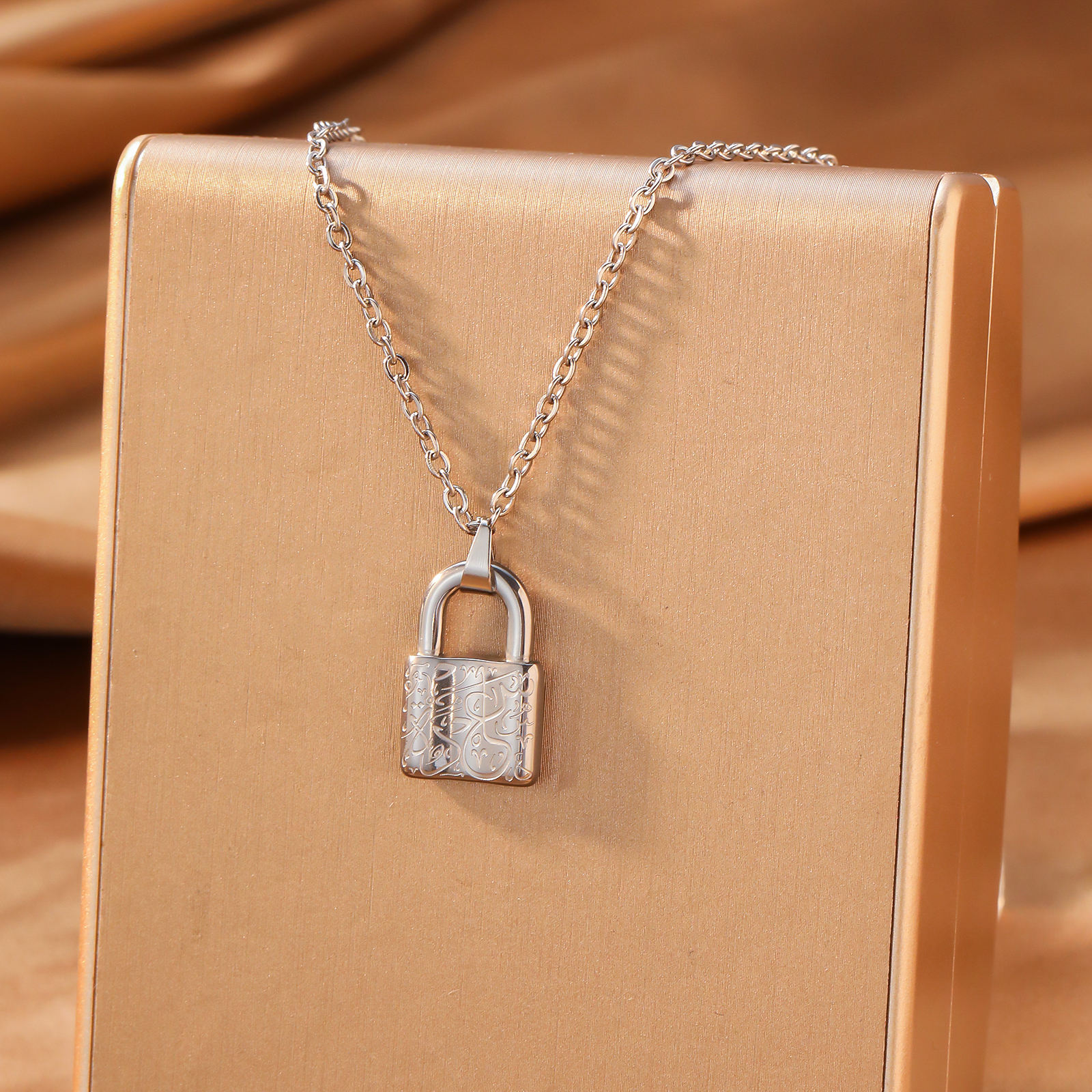 Silver lock pendant necklace on beige gift box