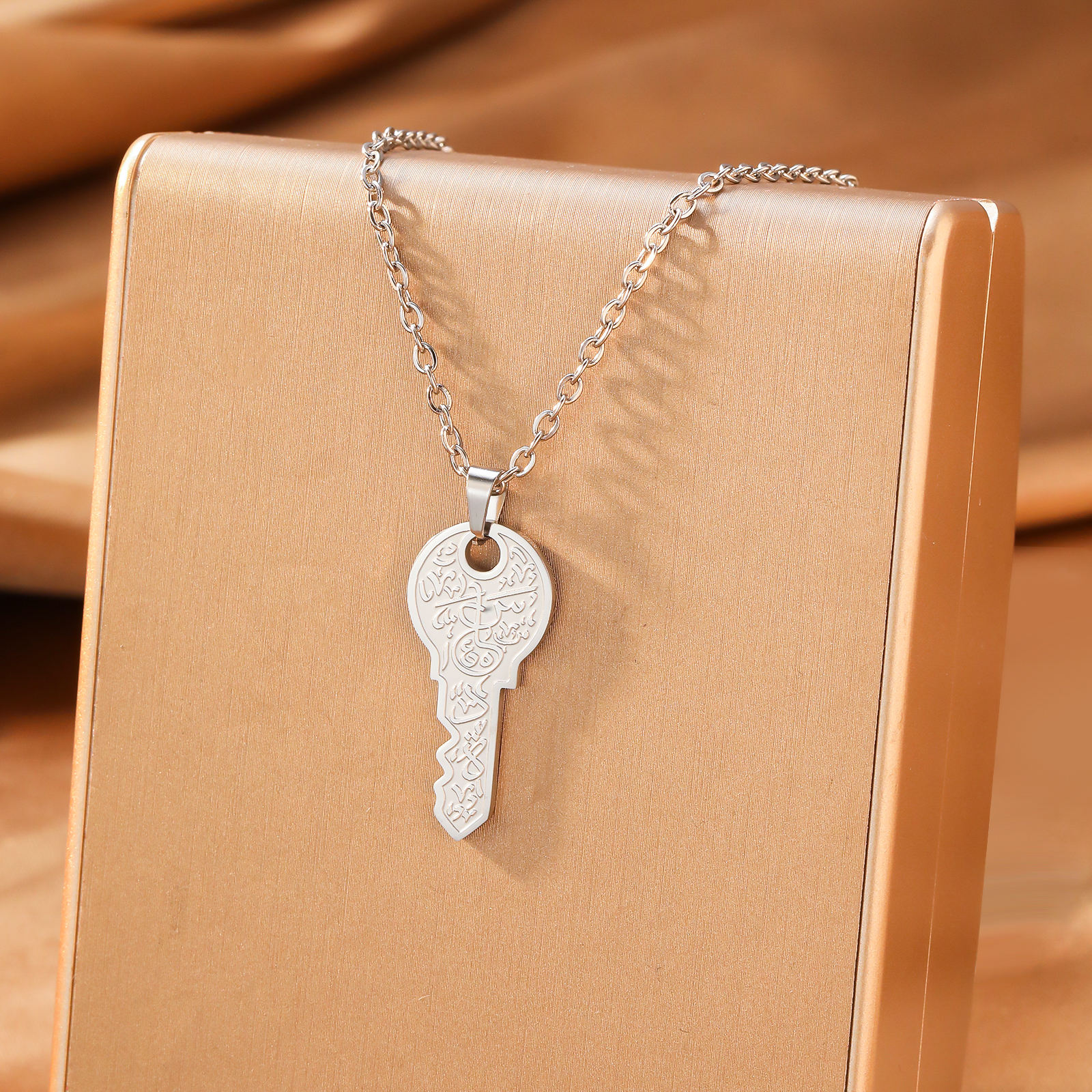 Silver key pendant necklace on beige gift box