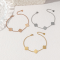 Four-leaf clover charm bracelet in gold, silver and rose gold on white background