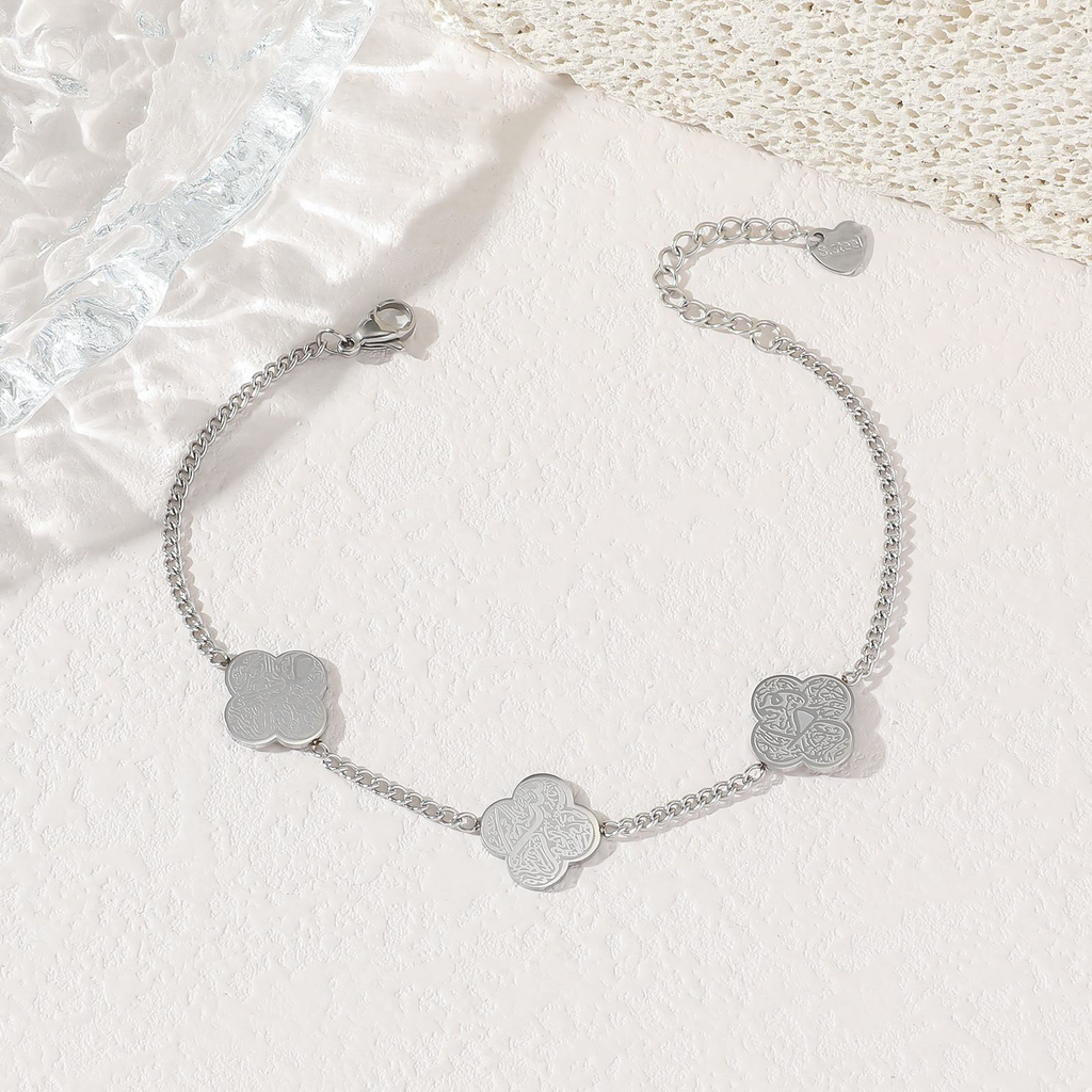 Silver four-leaf clover charm bracelet flat lay on white background