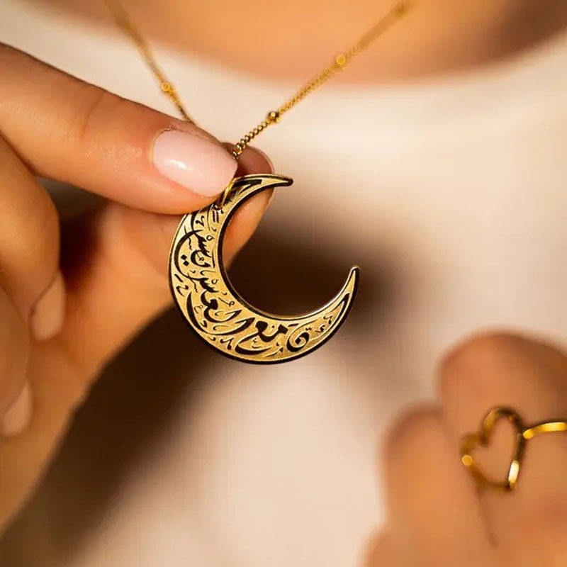 Close-up of gold crescent moon necklace - Meticulously engraved Arabic script jewelry for spiritual protection and peace