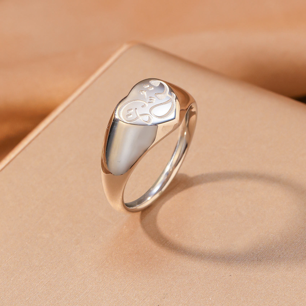 CIGAONI silver Hubb Arabic love calligraphy heart signet ring angled view on beige fabric surface