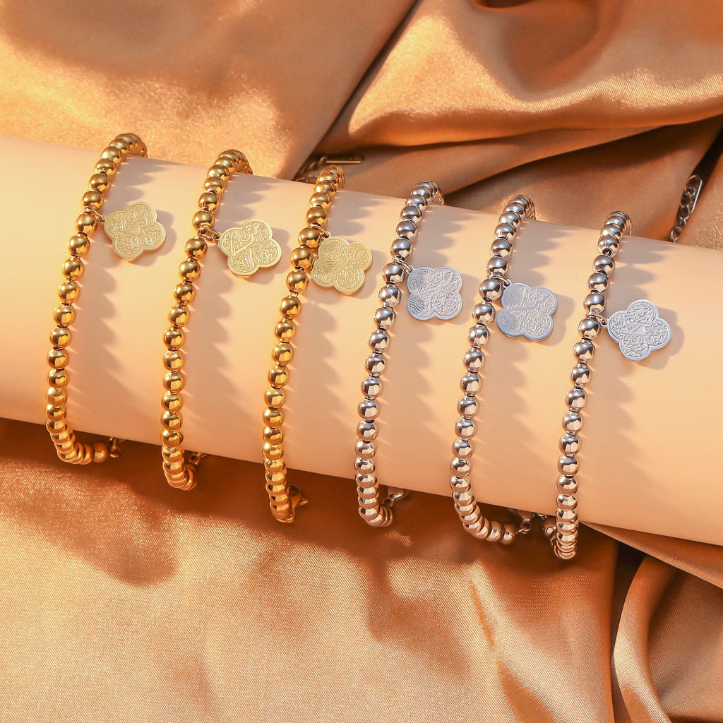 CIGAONI Clover of Virtue 18K gold bracelet on model's wrist, four-leaf quatrefoil charm engraved with Arabic calligraphy, beaded chain close-up lifestyle shot