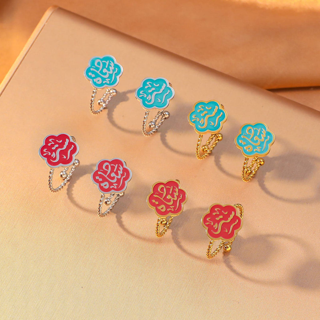 CIGAONI Bloom of Salam adjustable rings flat lay – teal and ruby red enamel Arabic calligraphy flower rings in 18K gold and silver, multiple variants displayed together
