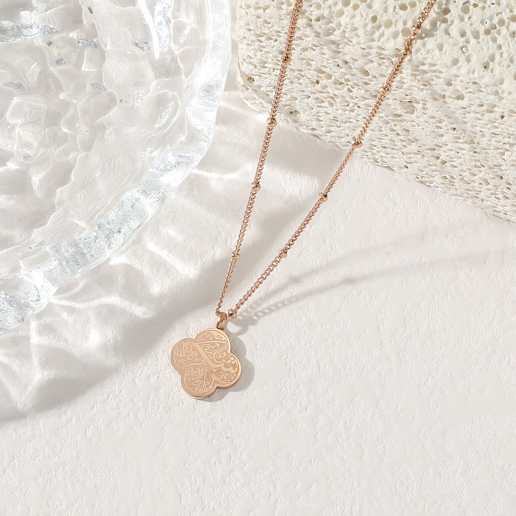 Rose gold four-leaf clover Sabr Arabic calligraphy pendant necklace on white background