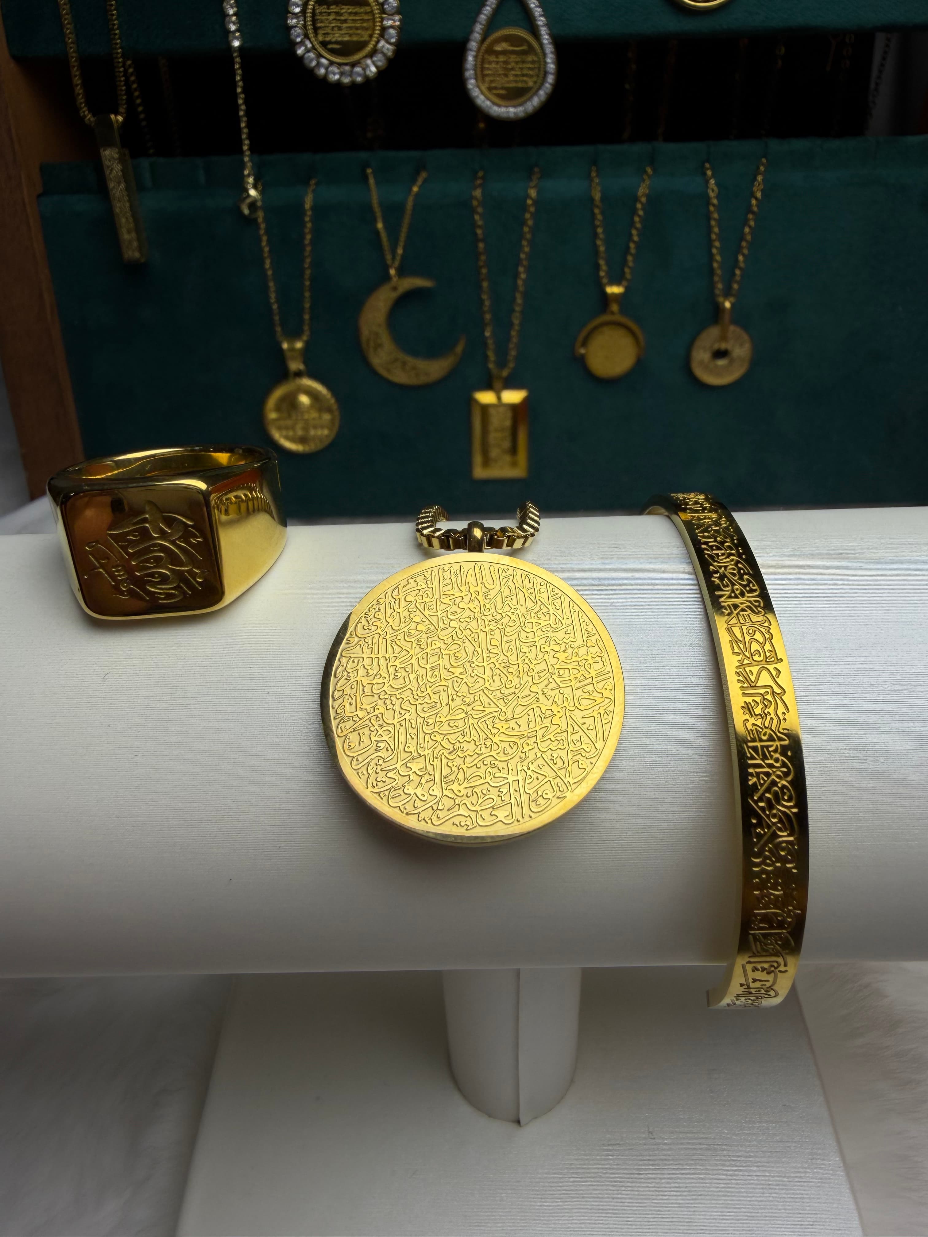CIGAONI Divine Circle 3-piece Islamic jewelry set in 18K gold – Ayatul Kursi medallion necklace, Allah signet ring, and Ayatul Kursi cuff bangle displayed on white jewelry stand
