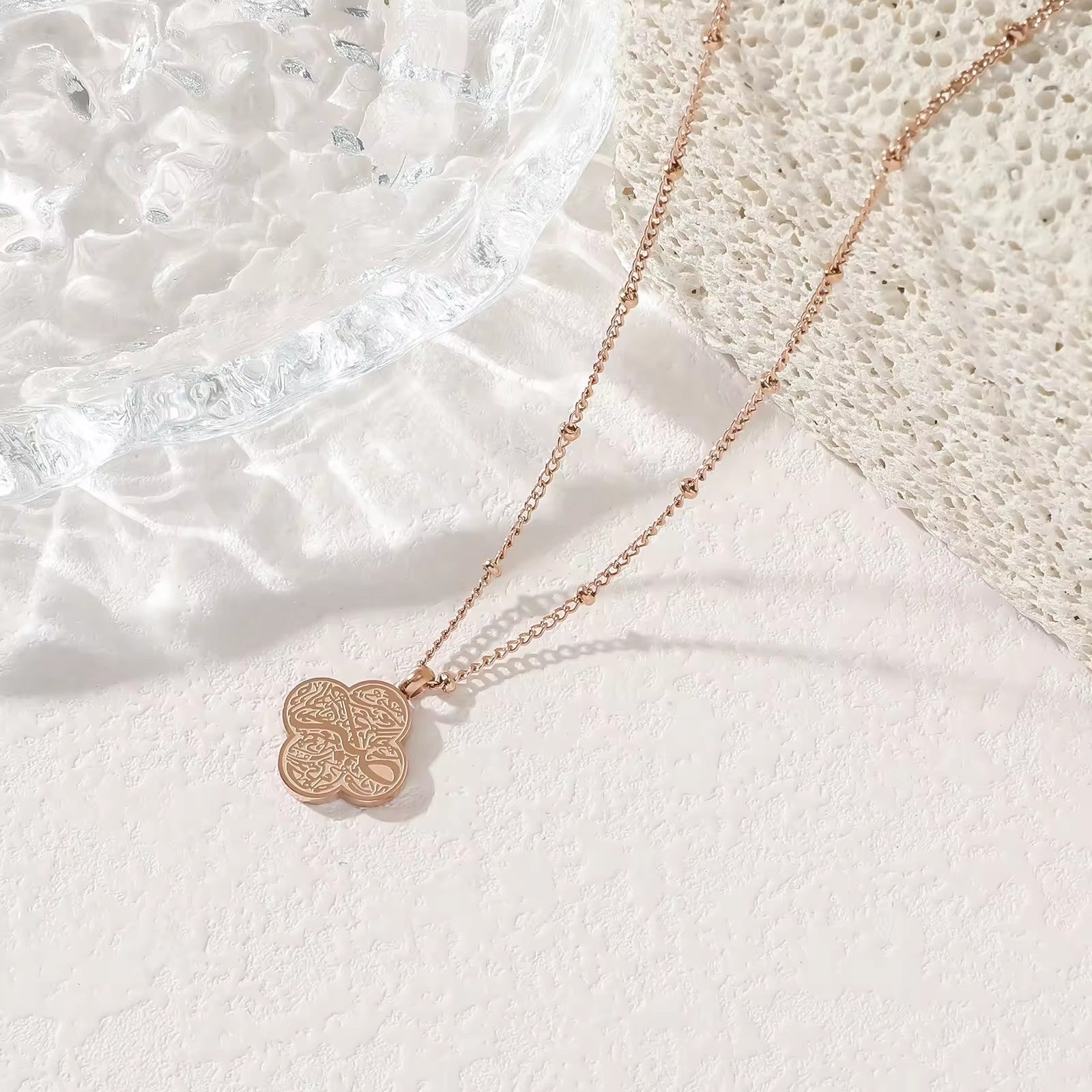 Silver four-leaf clover Tawakkul Arabic calligraphy pendant necklace on white background