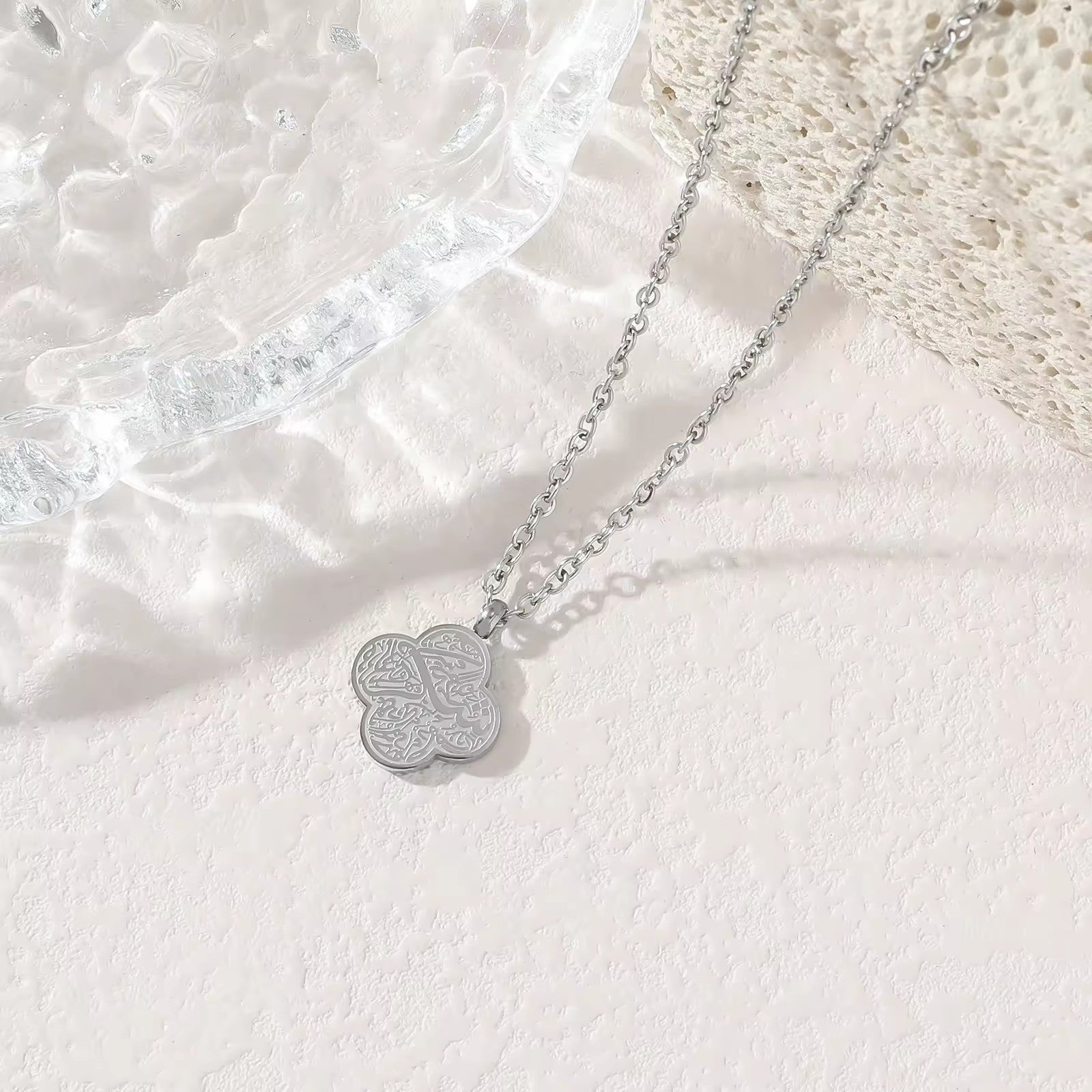 Silver four-leaf clover Sabr Arabic calligraphy pendant necklace on white background