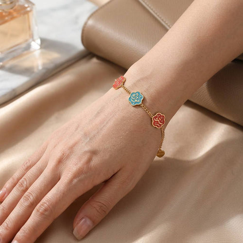 Woman wearing CIGAONI Floral Faith Bracelet – Gold chain with blue and red enamel Arabic calligraphy flower charms on wrist

