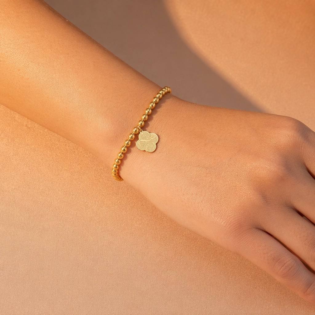 CIGAONI Clover of Virtue gold beaded bracelet worn on wrist, 18K gold quatrefoil Arabic calligraphy charm, lobster clasp with extender chain, 316L stainless steel