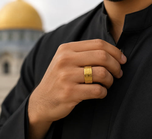 Man wearing CIGAONI Ayatul Kursi Gold Ring with Arabic calligraphy engraving, styled with black outfit against mosque backdrop