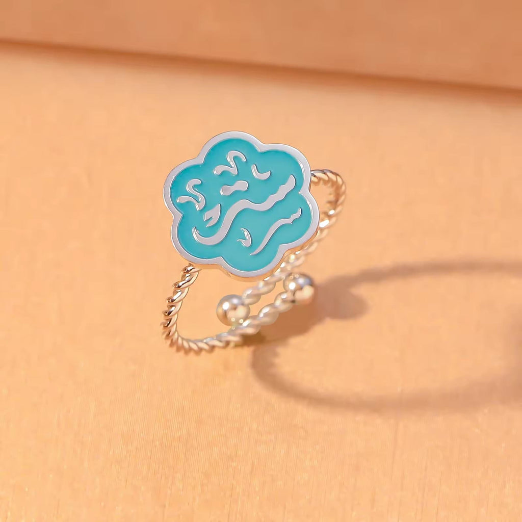 CIGAONI Bloom of Salam teal enamel ring in polished silver – overhead flat lay on warm skin-tone background

