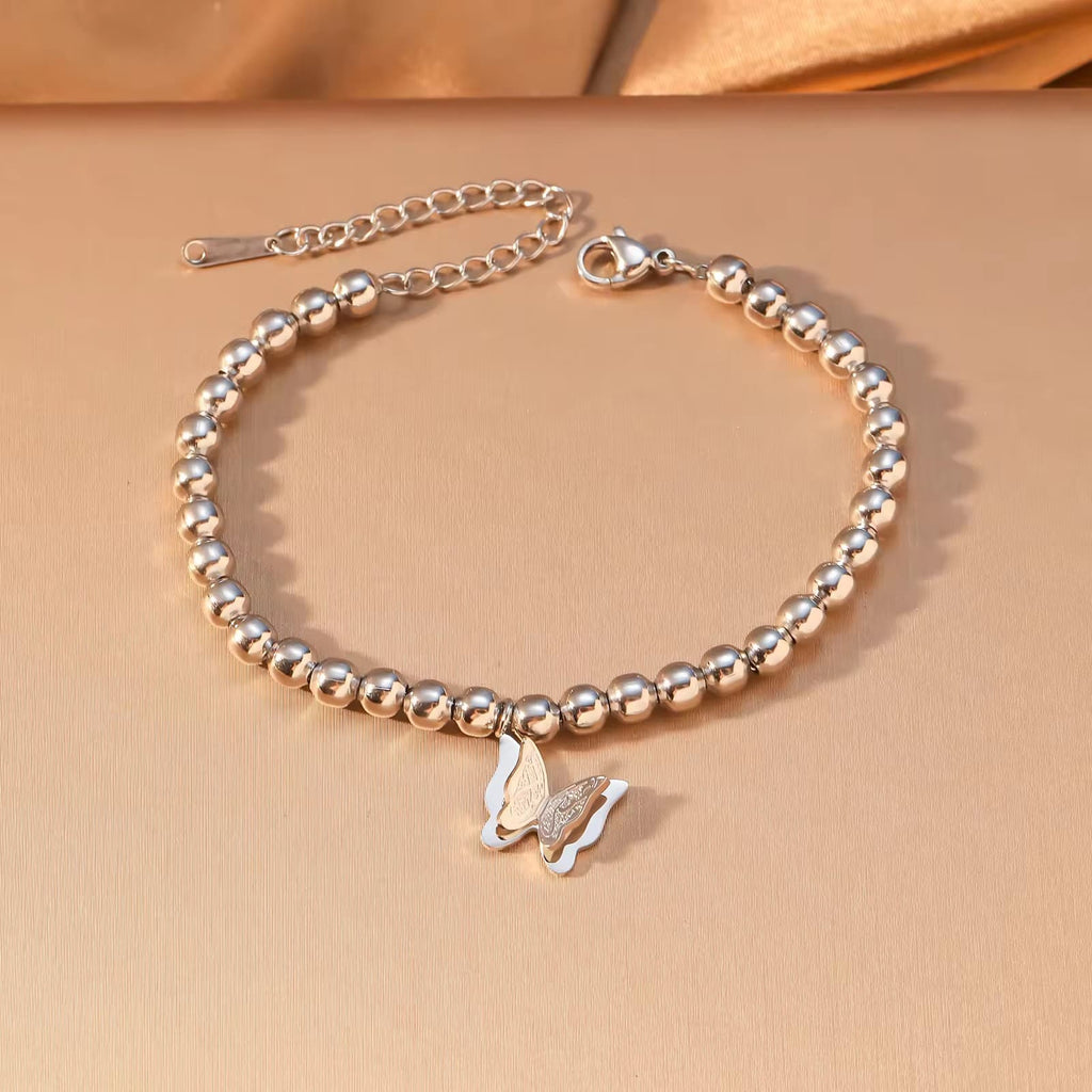 CIGAONI Wings of Amal silver butterfly beaded bracelet, polished 316L stainless steel, lobster clasp with extender chain, flat lay on neutral background

