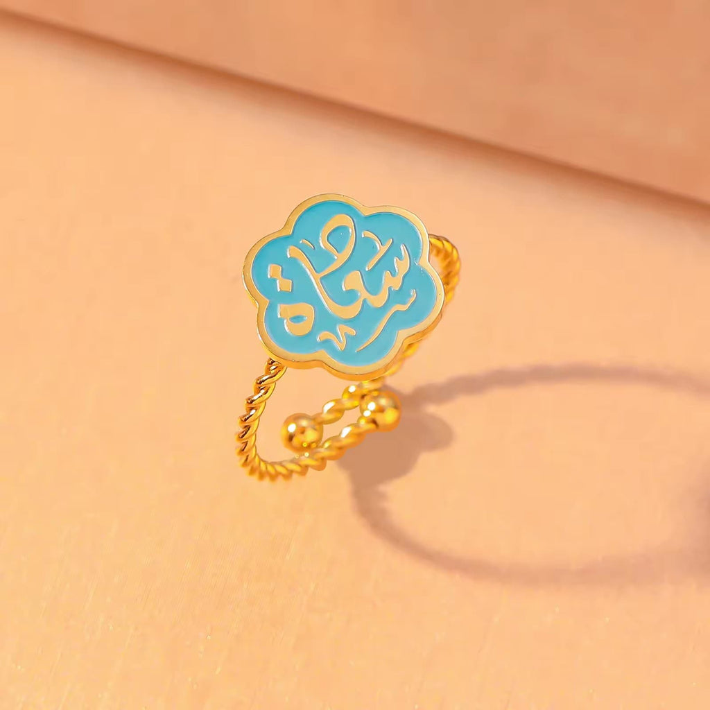 CIGAONI Bloom of Salam teal enamel ring in polished silver – Arabic calligraphy Salam detail visible on six-petal flower

