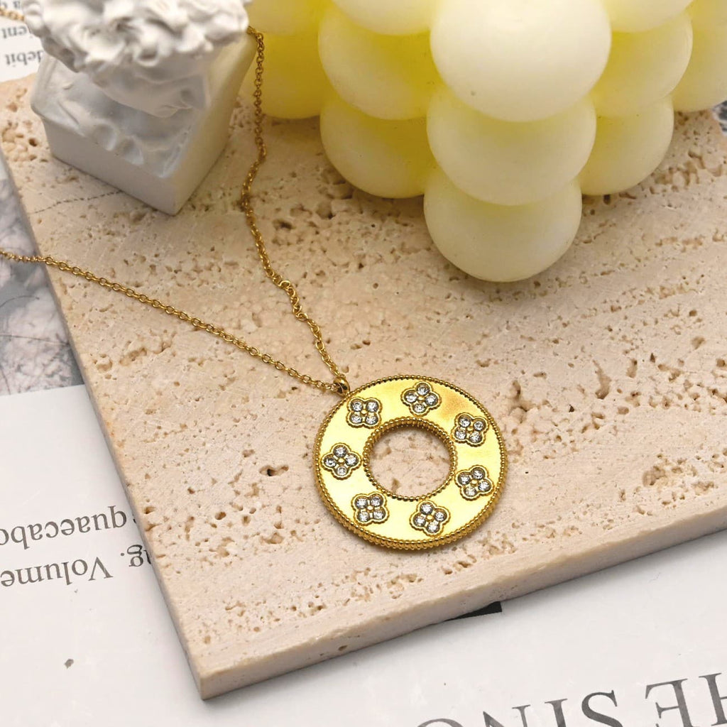 Gold hollow clover round pendant necklace flat lay with candle - CIGAONI