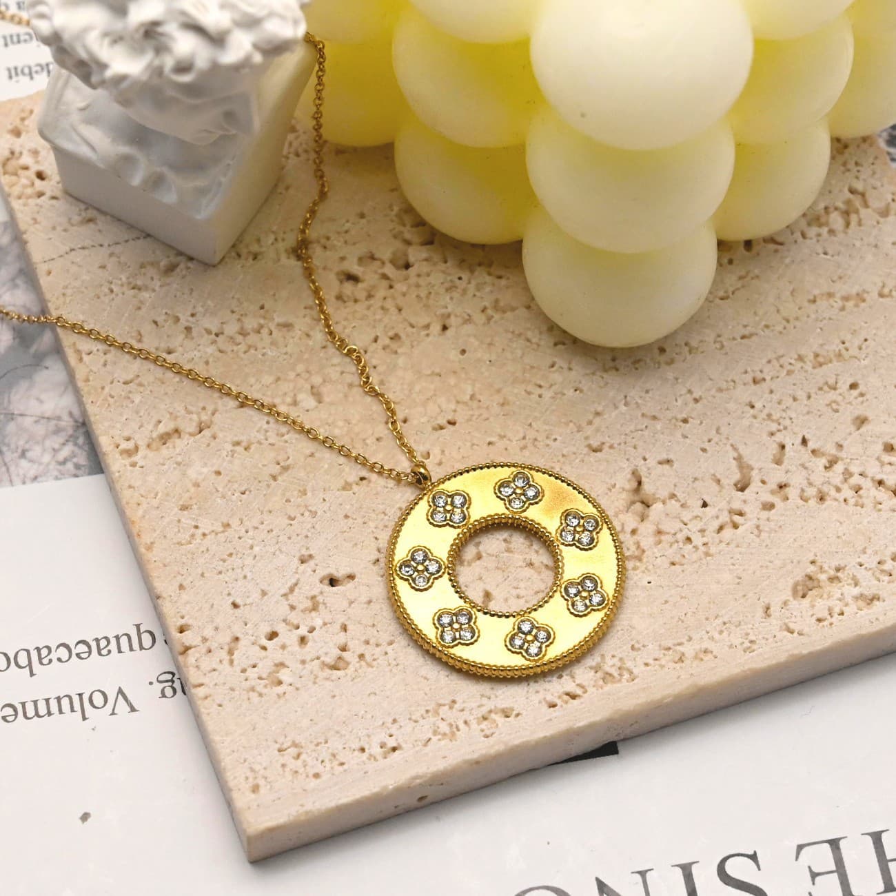 Gold hollow clover round pendant necklace flat lay with candle - CIGAONI