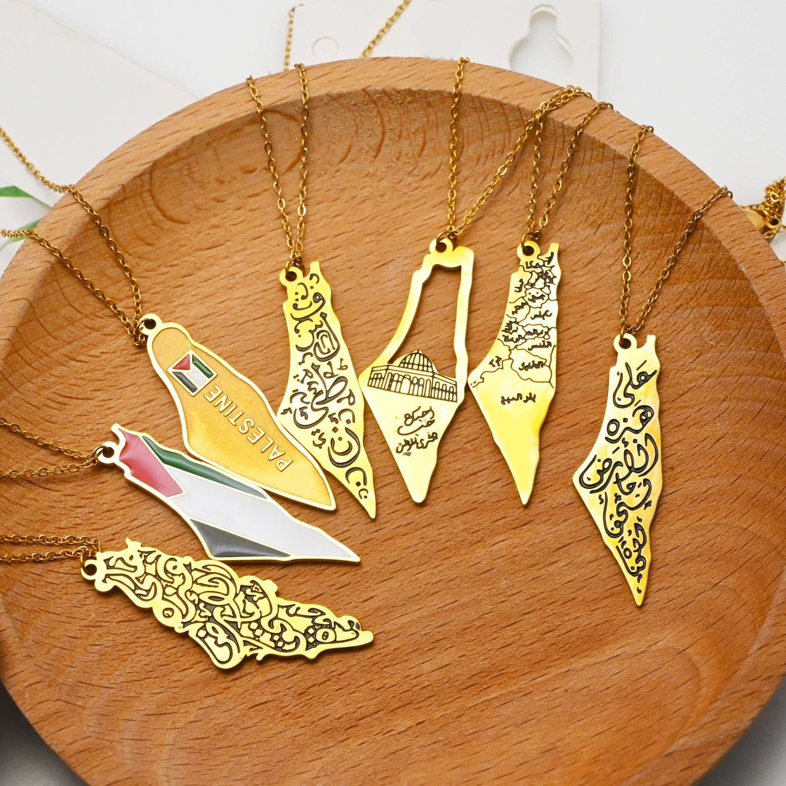 Gold Palestine map pendant necklaces collection flat lay on wooden plate - CIGAONI