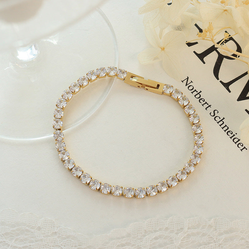 CIGAONI Pure Brilliance Gold Tennis Bracelet – Round Brilliant Clear Cubic Zirconia, Classic Four-Prong Setting, Secure Folding Clasp, Flat Lay on White Background