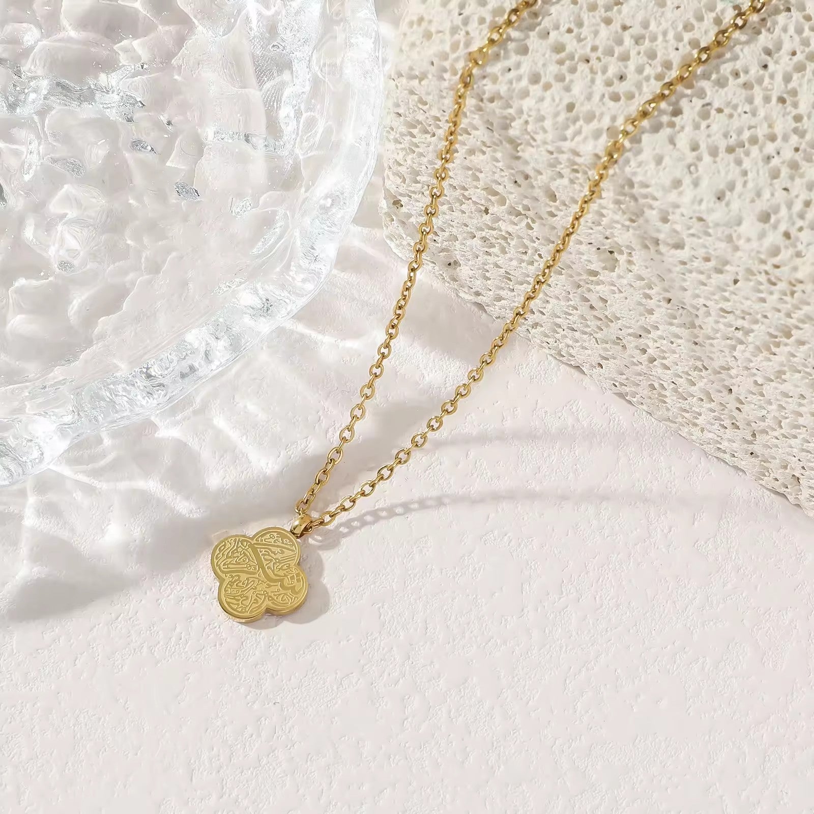 Gold four-leaf clover Shukr Arabic calligraphy pendant necklace on white background